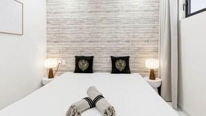A modern hotel room with a large bed, two bedside lamps, and a textured wall. - D434 - Amazing Apartment with Balcony (Sint Maarten)