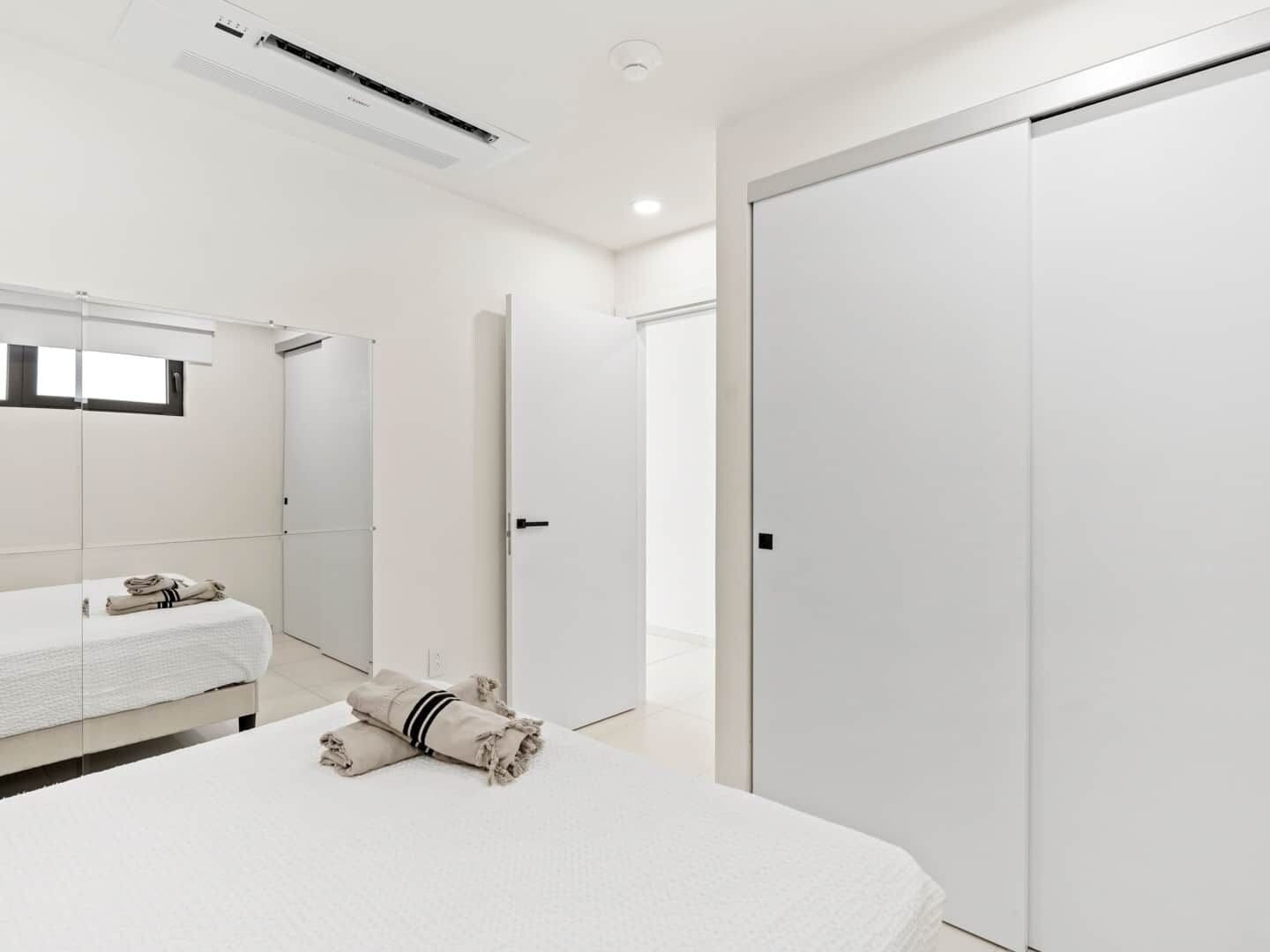 A modern hotel room with a bed, a wardrobe, and a bathroom mirror.