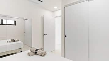 A modern hotel room with a bed, a wardrobe, and a bathroom mirror.