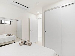 A modern hotel room with a bed, a wardrobe, and a bathroom mirror. - D416 – Relaxing apartment with Balcony (Sint Maarten)