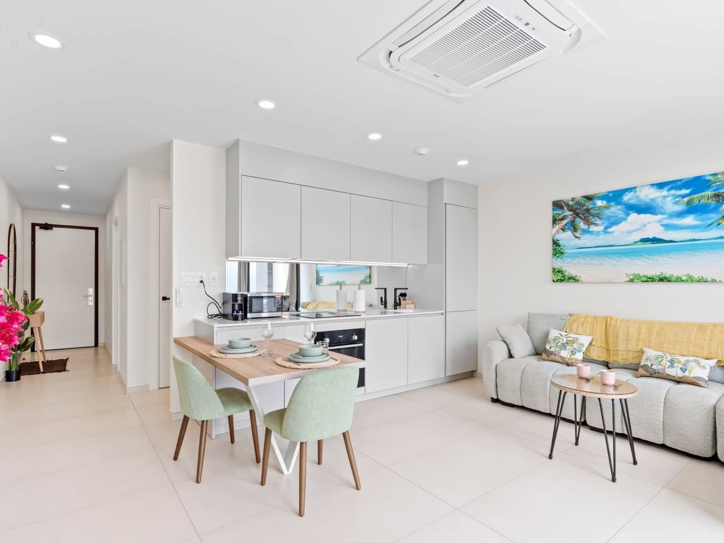 A modern kitchen with white cabinets, a dining table with chairs, a sofa, and a small coffee table.