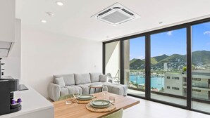 A modern living room with a dining area, large windows, and a view of a marina. - D416 – Relaxing apartment with Balcony (Sint Maarten)