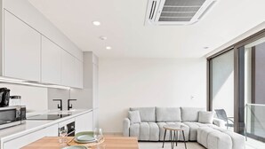 A modern kitchen with white cabinets, a dining table set for two, and a grey sofa in the living area. - D416 – Relaxing apartment with Balcony (Sint Maarten)