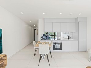 A modern kitchen with white cabinetry, a dining table with chairs, and a built-in dishwasher. - C335 – Comfortable Lagoon View Apartment (Sint Maarten)