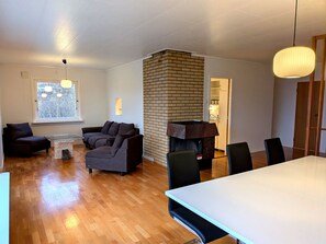 Una sala de estar moderna con chimenea, un comedor con mesa y sillas, y un sofá.
