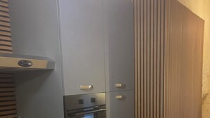 Et køkken med lysegrå skabe, indbygget ovn og mikroovn.
