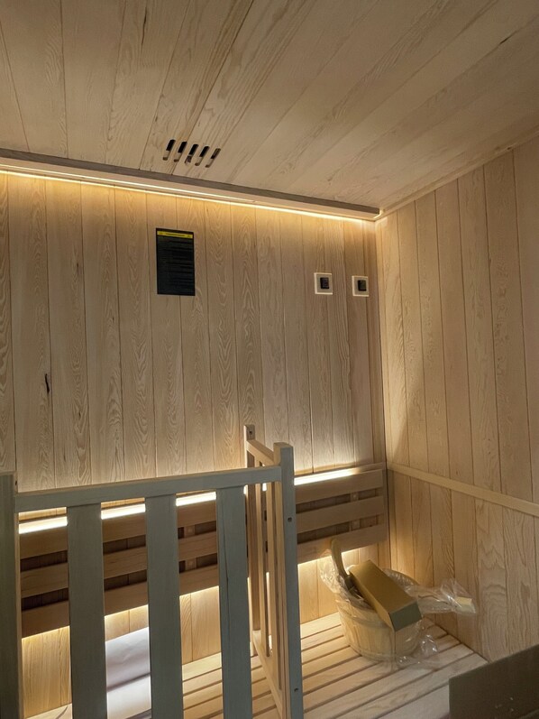 Une salle de sauna en bois, avec des bancs et un banc au premier plan.