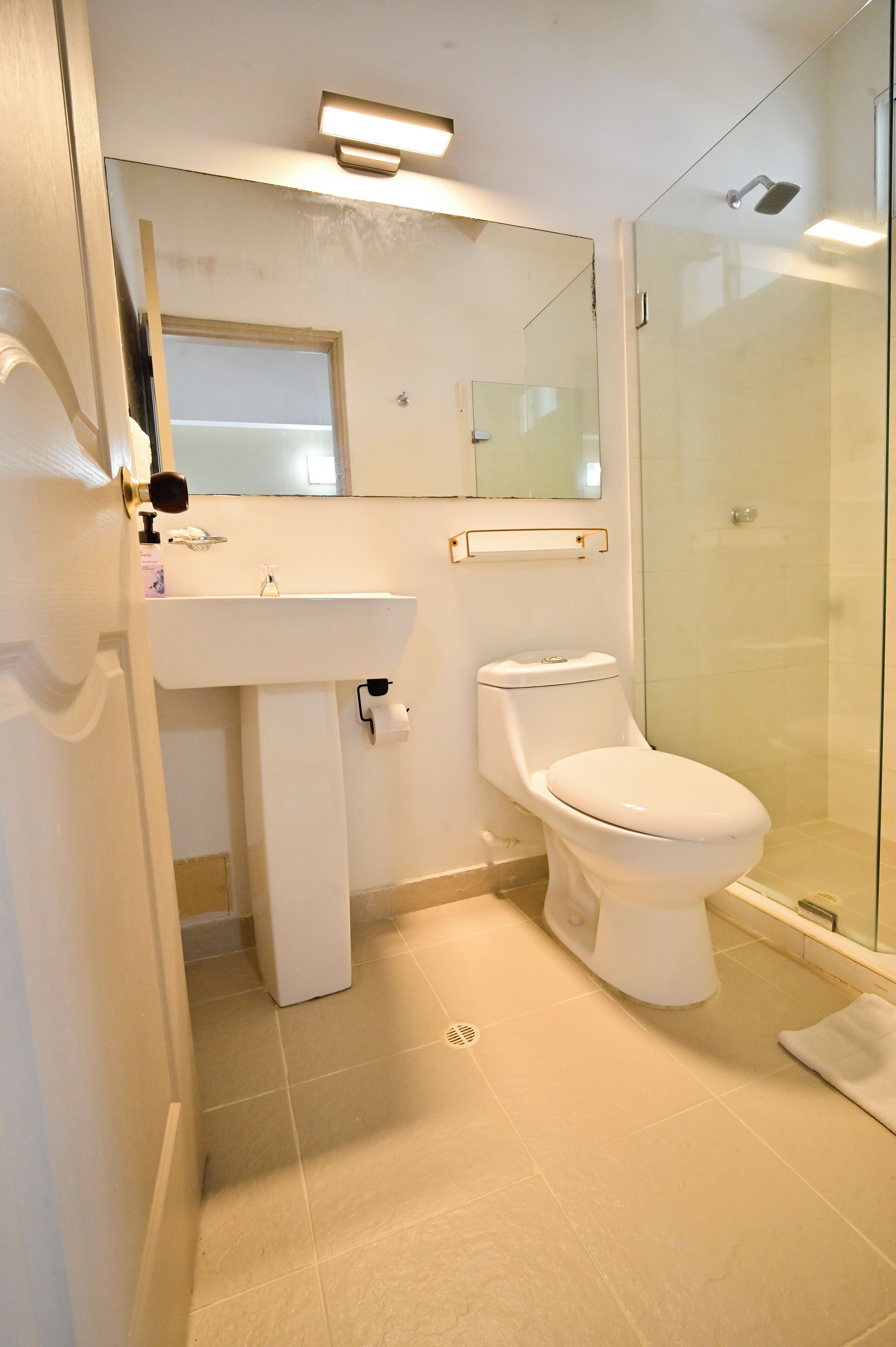 Un baño con inodoro, lavabo y cabina de ducha de vidrio.