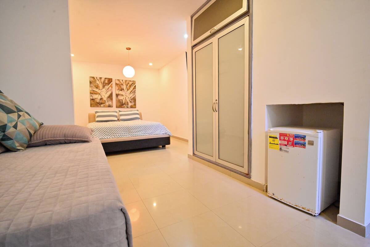 A bedroom with a bed, a wardrobe, and a refrigerator.