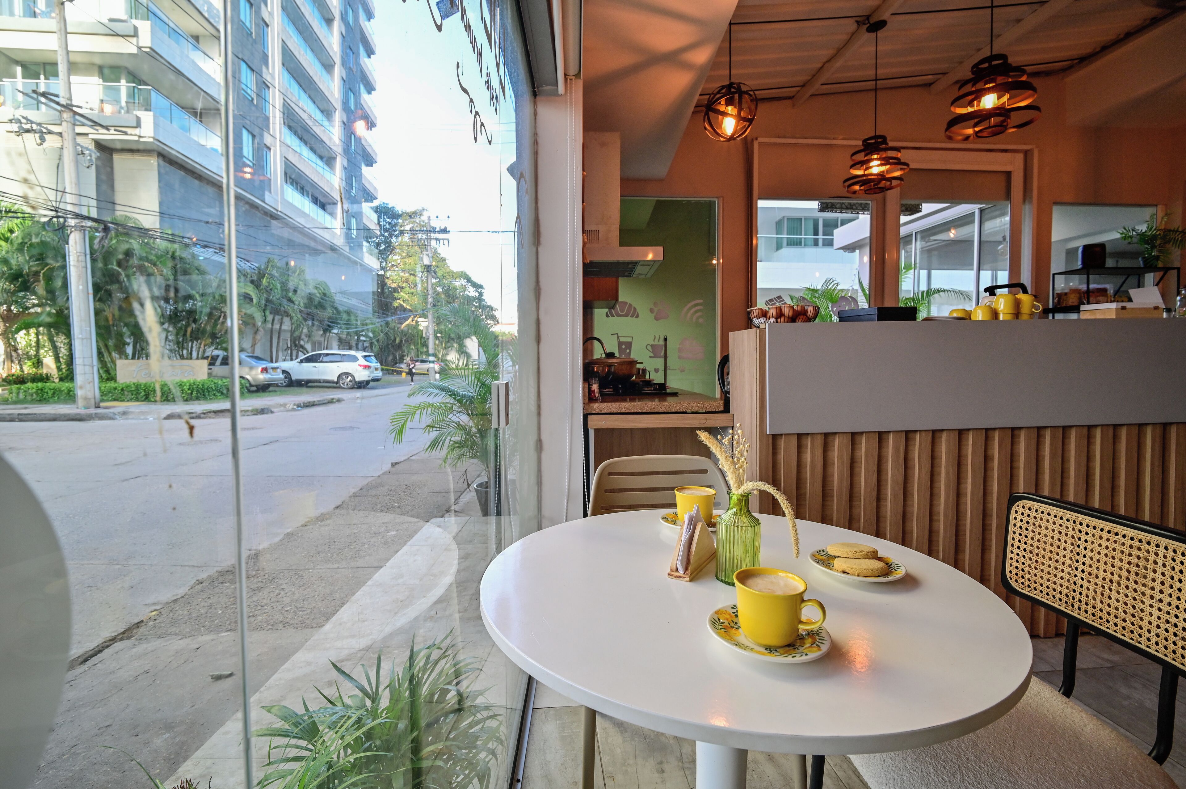 A cafe with a round table, yellow cups, and a view of the street.