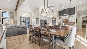 Een moderne keuken met een centraal eiland, een eethoek met houten stoelen, en een gezellige woonkamer met een bank.