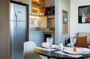 A modern kitchen with a built-in refrigerator, a dining table set with plates and glasses, and a small plant on the counter.