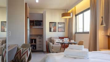 Ein Hotelzimmer mit Bett, Esstisch, Stuhl, Sofa und einer Küchenzeile.