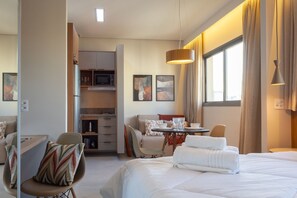 A hotel room with a bed, a dining table, a chair, a sofa, and a kitchenette. - AD330 - 1002 (São Paulo)