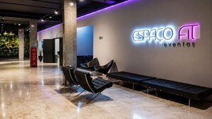 Um interior moderno com área de estar, uma placa na parede com a inscrição 'ESPAÇO EVENTOS' e um extintor de incêndio.