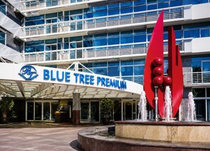 A hotel entrance with a Blue Tree Premium sign, a water feature, and a modern building facade. - AD330 - 1002 (São Paulo)