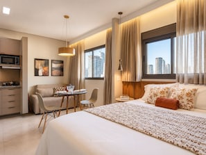 A hotel room with a bed, a dining area, a kitchen, and a view of the cityscape. - AD330 - 1002 (São Paulo)