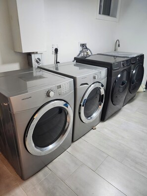 A laundry area with two front-loading washing machines and a dryer. - Forest City (room for one person) #1 (London)