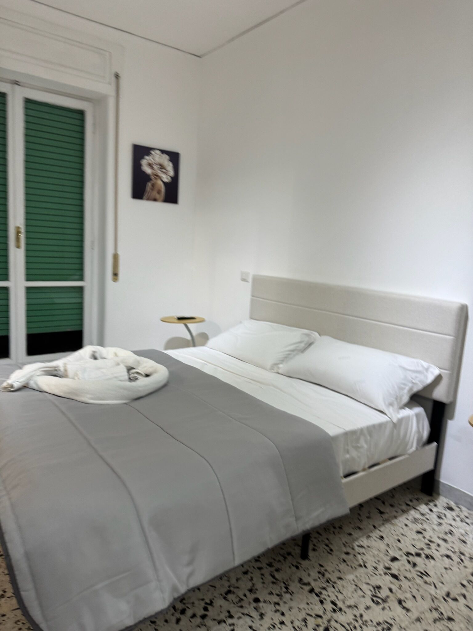 A bedroom with a bed, a bedside table, and a green door.