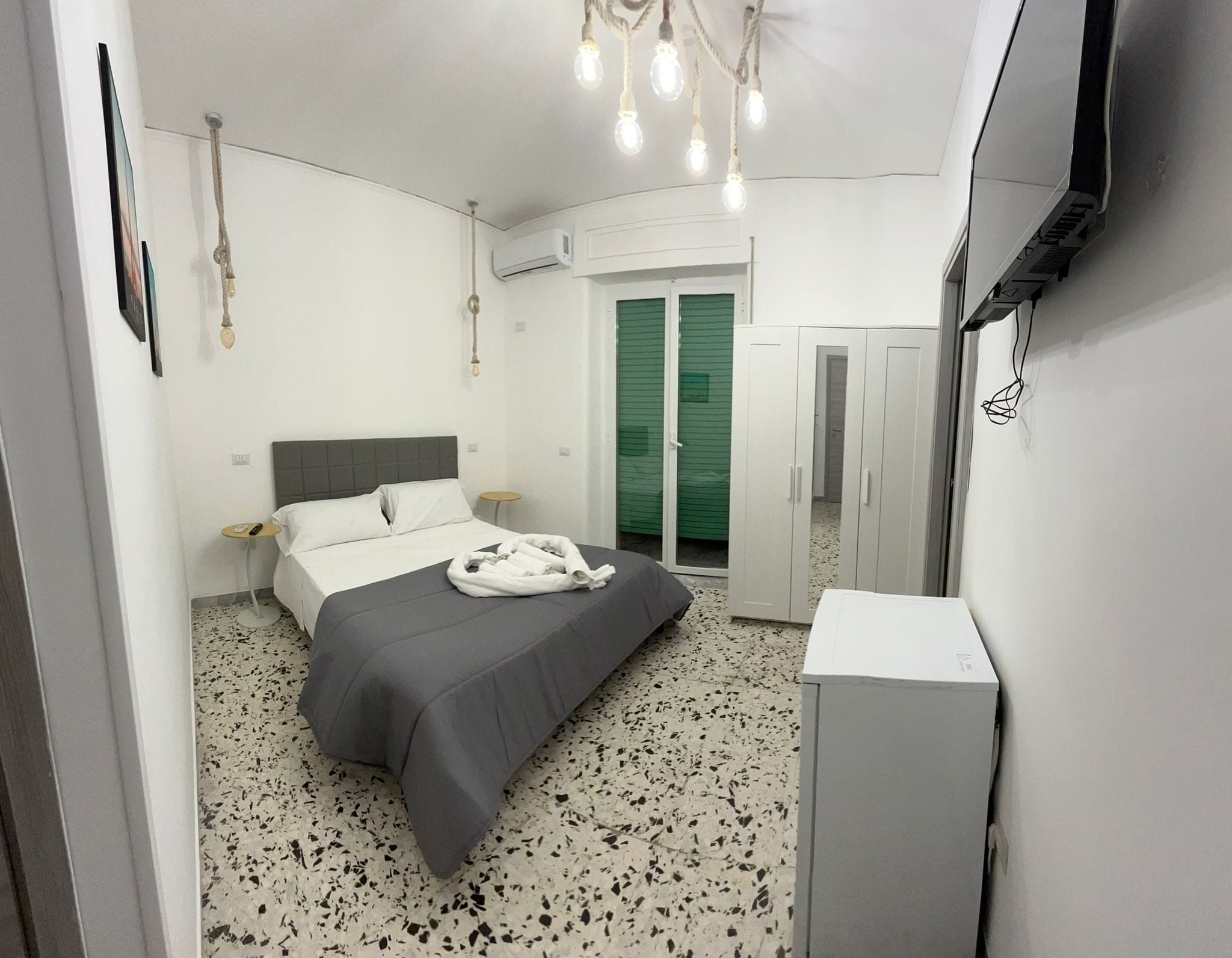Une chambre à coucher avec un lit, une petite table ronde, un téléviseur et une armoire.