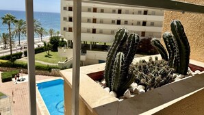 Un balcon donnant sur une piscine, des palmiers et un immeuble doté de nombreux balcons.