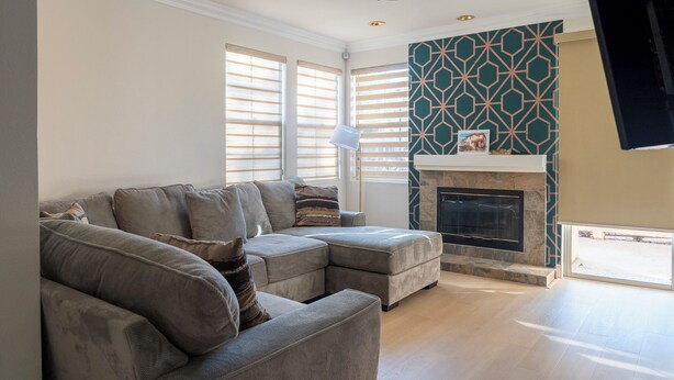 A modern living room with a sectional sofa, a fireplace, and large windows. - Beautiful 2-bedroom condo in cool San Diego close to the mall! (San Diego)