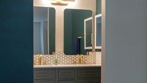 A modern bathroom with a white vanity, a mirror, and a light fixture above the sink. - Beautiful 2-bedroom condo in cool San Diego close to the mall! (San Diego)