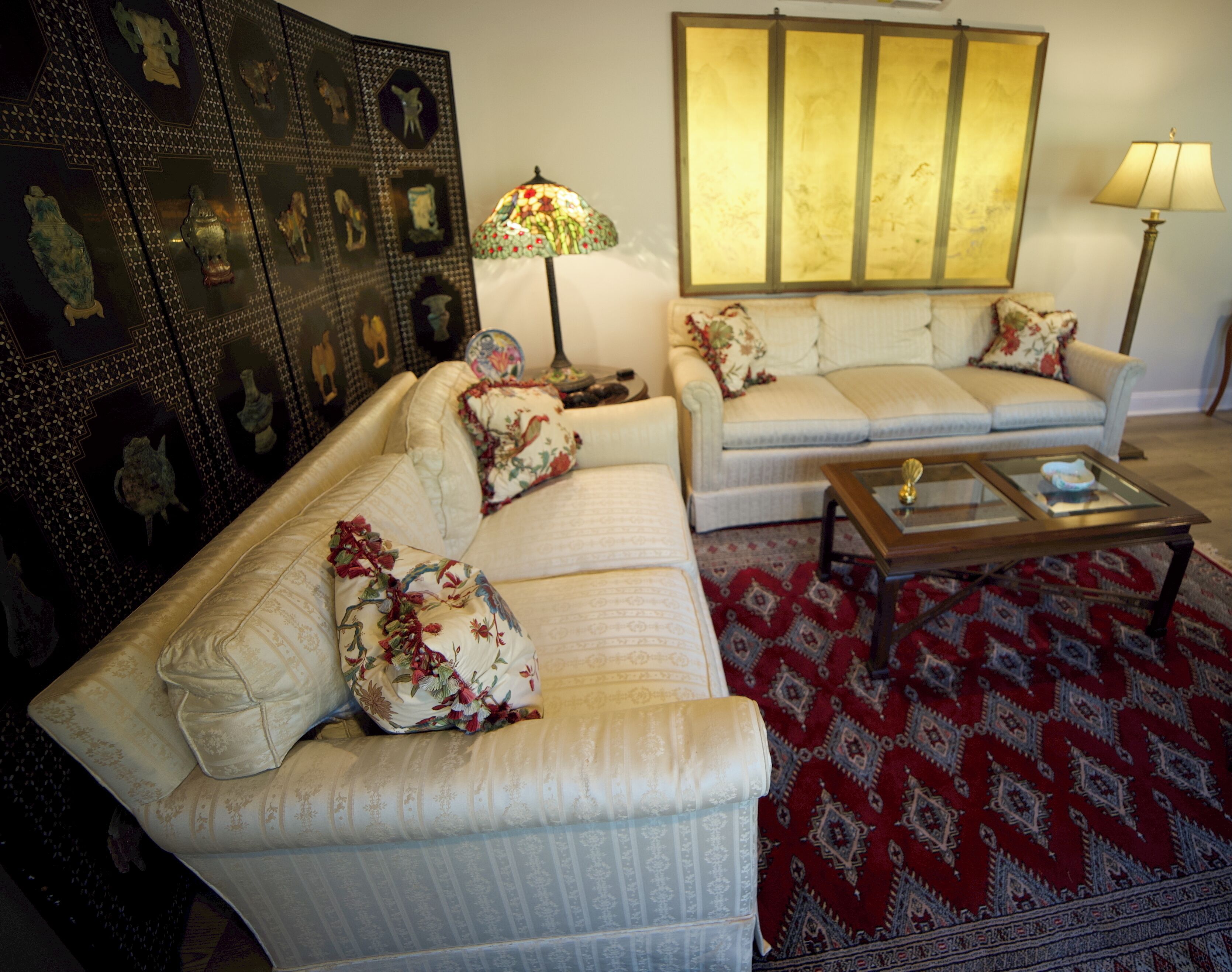 A living room with two sofas, a coffee table, a lamp, and a decorative wall panel.