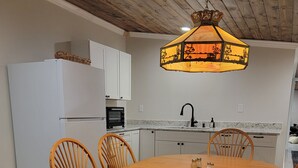 A modern kitchen with white cabinets, a built-in oven, and a dining area with a wooden table and chairs. - Spacious Beautiful Unique place to stay in Morganton, NC. (Morganton)