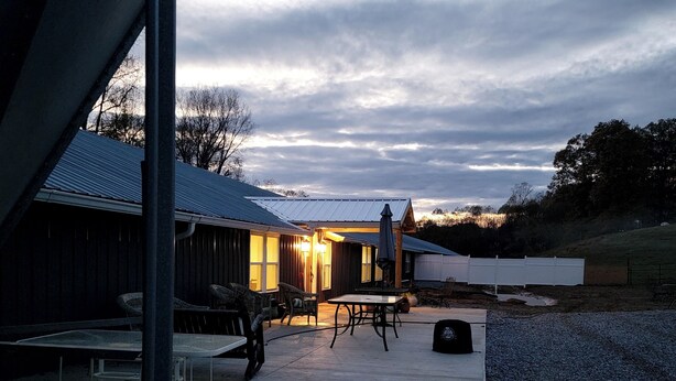 A building with a covered patio area, outdoor seating, and a gravel ground. - Spacious Beautiful Unique place to stay in Morganton, NC. (Morganton)