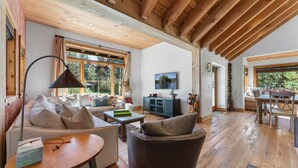 A spacious living area with a wooden ceiling, a sofa set, a television, and a dining table. - A Serene Mountain Autumn/Fall Getaway (Soda Springs)