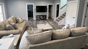Ein modernes Wohnzimmer mit einer Eckcouch, einem Flachbildfernseher und einer Treppe zu einer weiteren Ebene.
