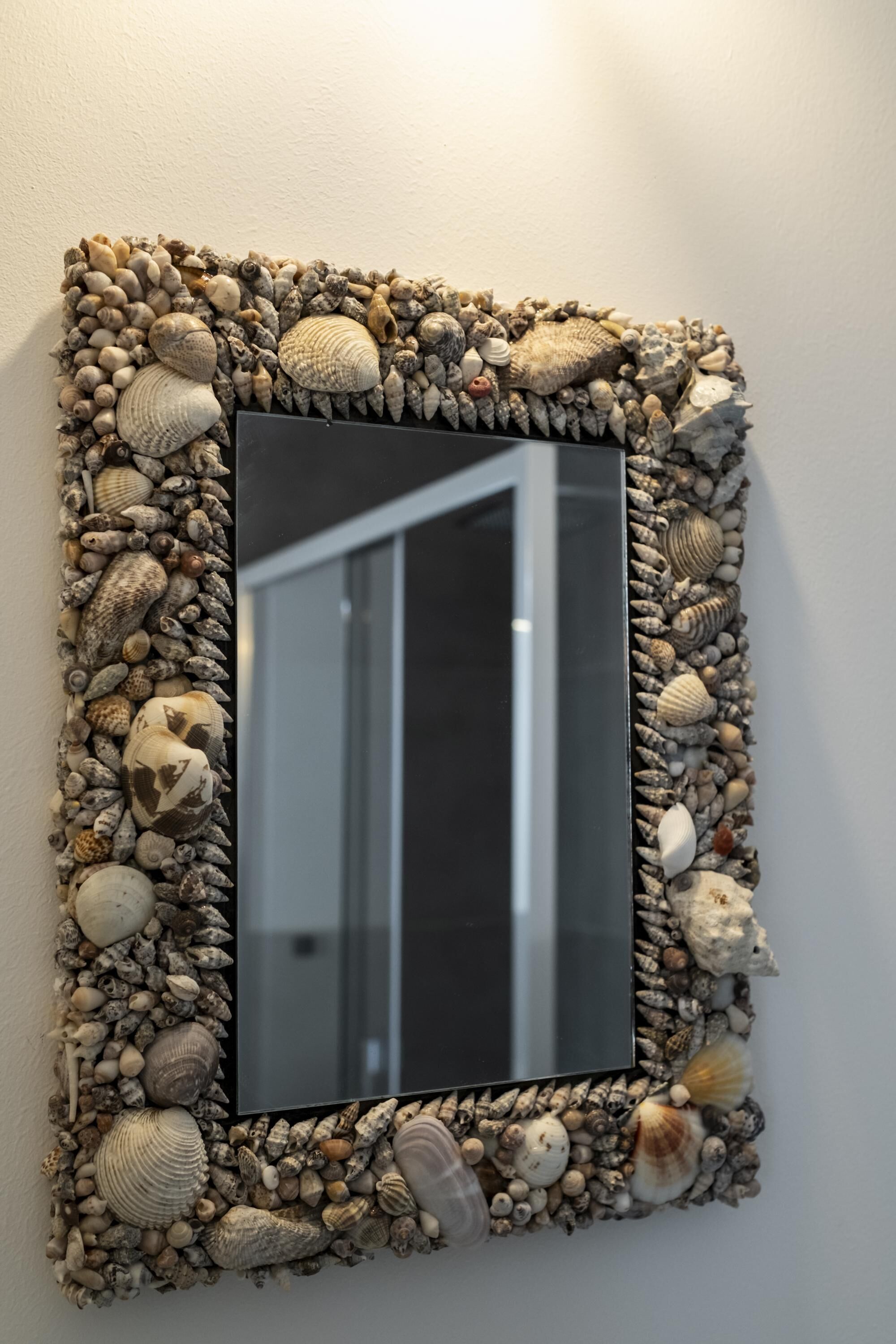 A mirror framed with a collection of seashells and stones.