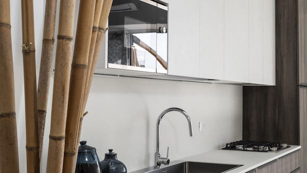 Une cuisine moderne avec des meubles blancs, un évier en acier inoxydable et une cuisinière à gaz.