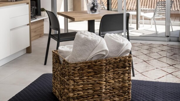 Une cuisine moderne avec un plan de travail en bois, un coin repas avec une table et des chaises, et une grande porte-fenêtre coulissante donnant sur un balcon avec vue sur les montagnes.