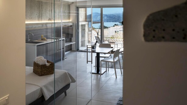 Une chambre moderne comprenant un lit, une petite cuisine et un coin repas avec vue sur la mer.