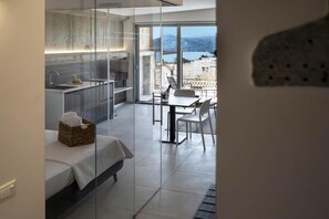 Ein modernes Zimmer mit Bett, einer kleinen Küche und einem Essbereich mit Meerblick.