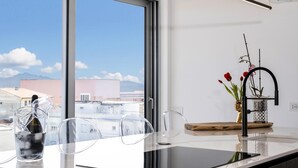 A modern kitchen with a large window, a black faucet, and a vase with flowers on the counter. - Attico Salia - La Maddalena (La maddalena)
