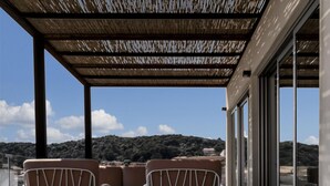 A hot tub with three chairs, a wooden deck, and a view of hills. - Attico Salia - La Maddalena (La maddalena)