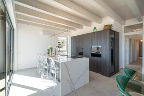 Eine moderne Küche mit einer Marmorinsel, transparenten Stühlen und einem grünen Sofa.