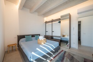 Ein Schlafzimmer mit einem großen Bett, einem Nachttisch, einem Spiegel und einem kleinen hölzernen Hocker.