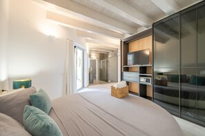 Et moderne soveværelse med en stor seng, fjernsyn og et walk-in closet.