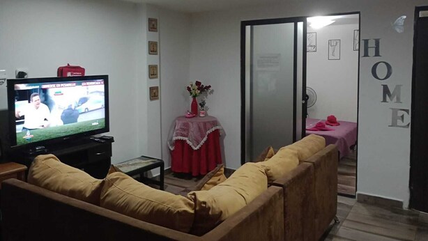 A living room with a television, a sofa, a small table with a vase, and a door labeled "HOME". - Nice and Comfortable Apartment on second floor#202 (Dosquebradas)