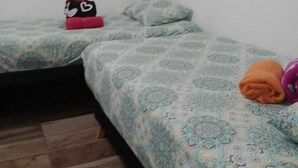 A small, clean room with two beds, a wooden floor, and a white wall with three small pictures. - Nice and Comfortable Apartment on second floor#202 (Dosquebradas)
