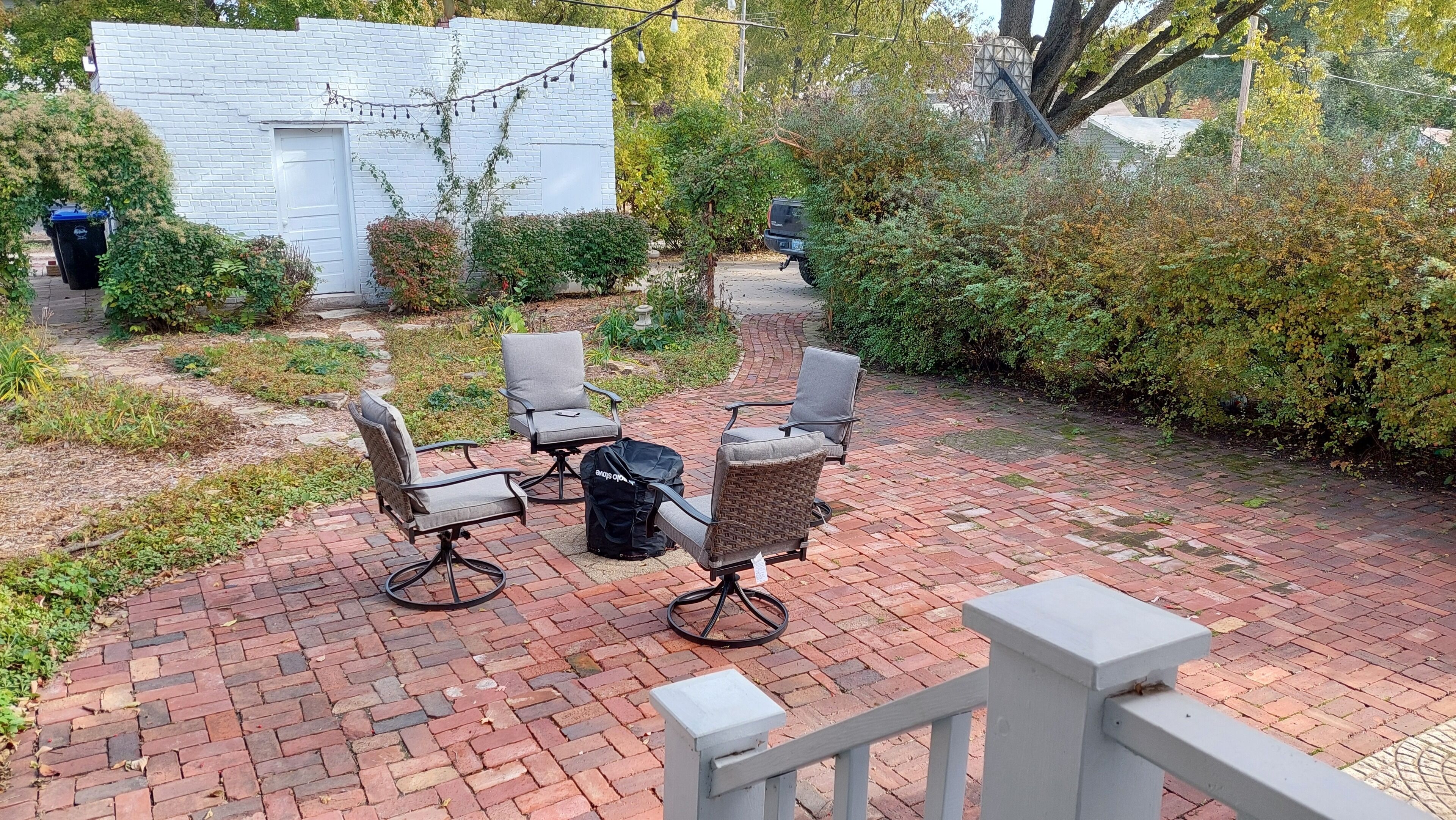 A patio with outdoor furniture, a white building, and a garden area.