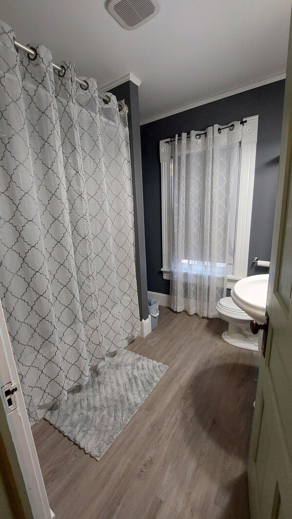 Un baño con cortina de ducha, inodoro y lavamanos.