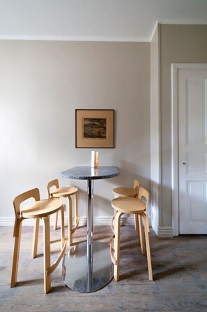 A round table with four wooden chairs in a room with a white door and a framed picture on the wall. - Stylish Historic Studio in the Heart of Helsinki (Helsinki)