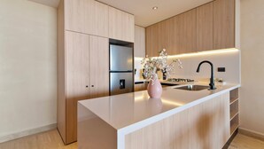 Una cocina moderna con armarios de madera, encimera blanca, pileta de acero inoxidable y un florero con flores.