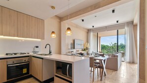 Una cocina moderna con una isla central, horno empotrado e iluminación colgante.