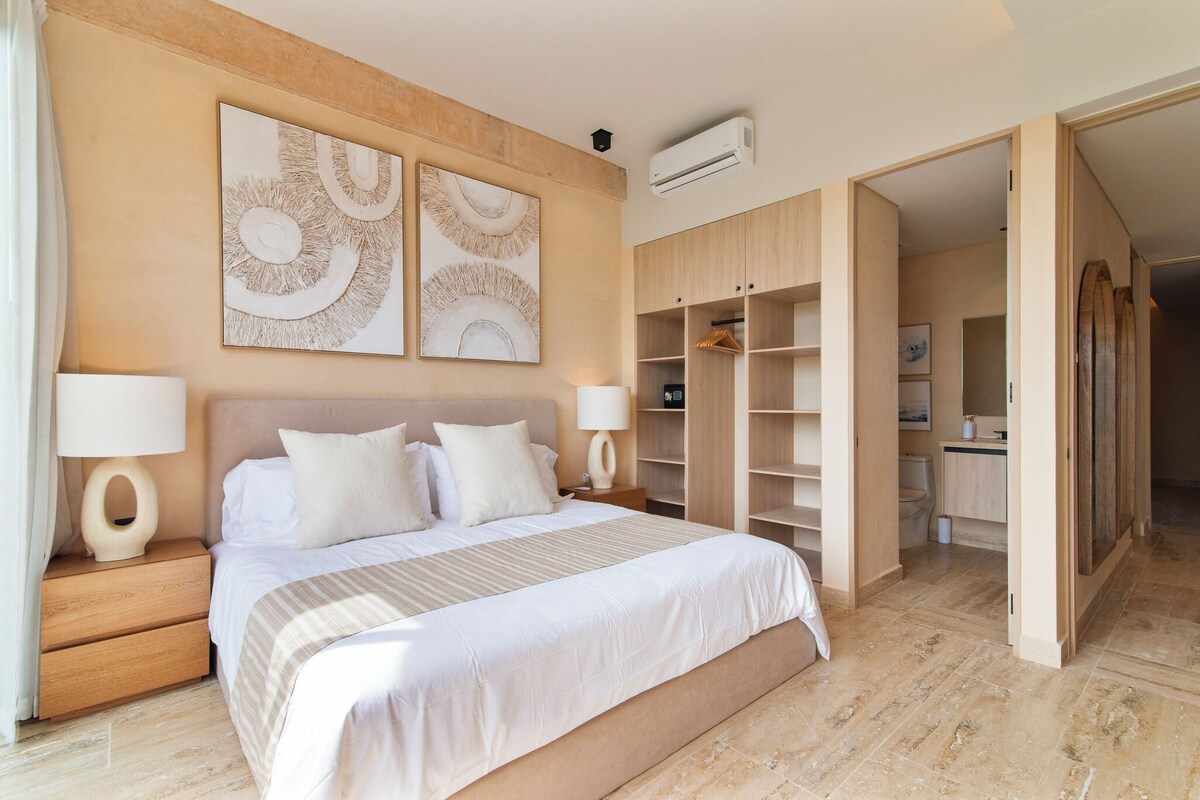Ein Schlafzimmer mit einem großen Bett, zwei Nachttischen, einem Kleiderschrank und einem begehbaren Kleiderschrank.